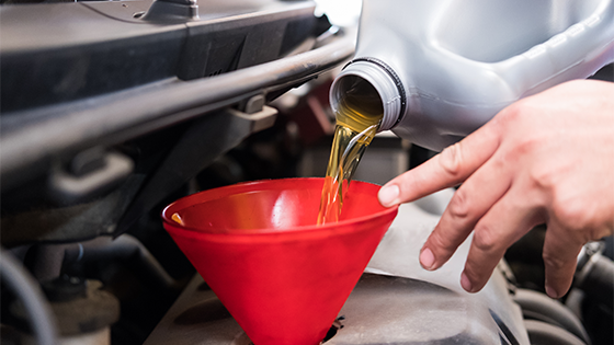 Midsection of a man pouring engine oil into a car through a funnel