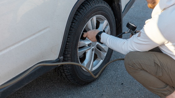 man checking car tire pressure car travel road trip